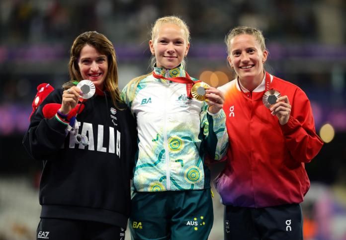 Three female athletes pose for a photo with their medals